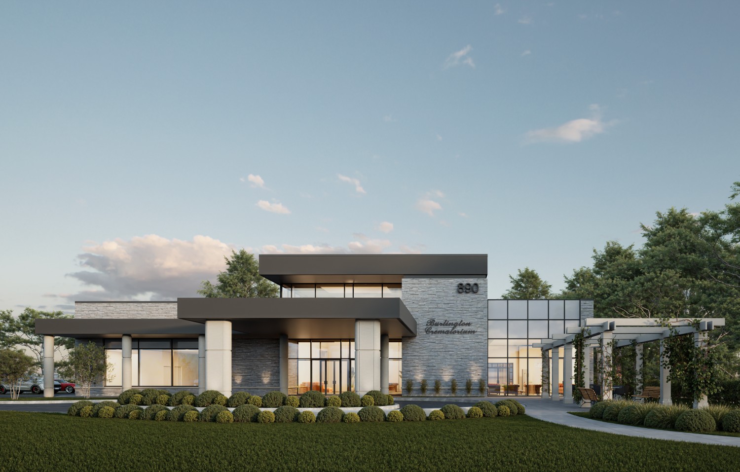 Modern two-story commercial building with large windows, flat roof, and landscaped surroundings under a partly cloudy sky.