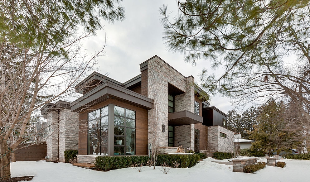 Modern two-story house with large windows and a wood and stone exterior at 1089 Lavender Lane, surrounded by bare trees and a snow-covered ground.