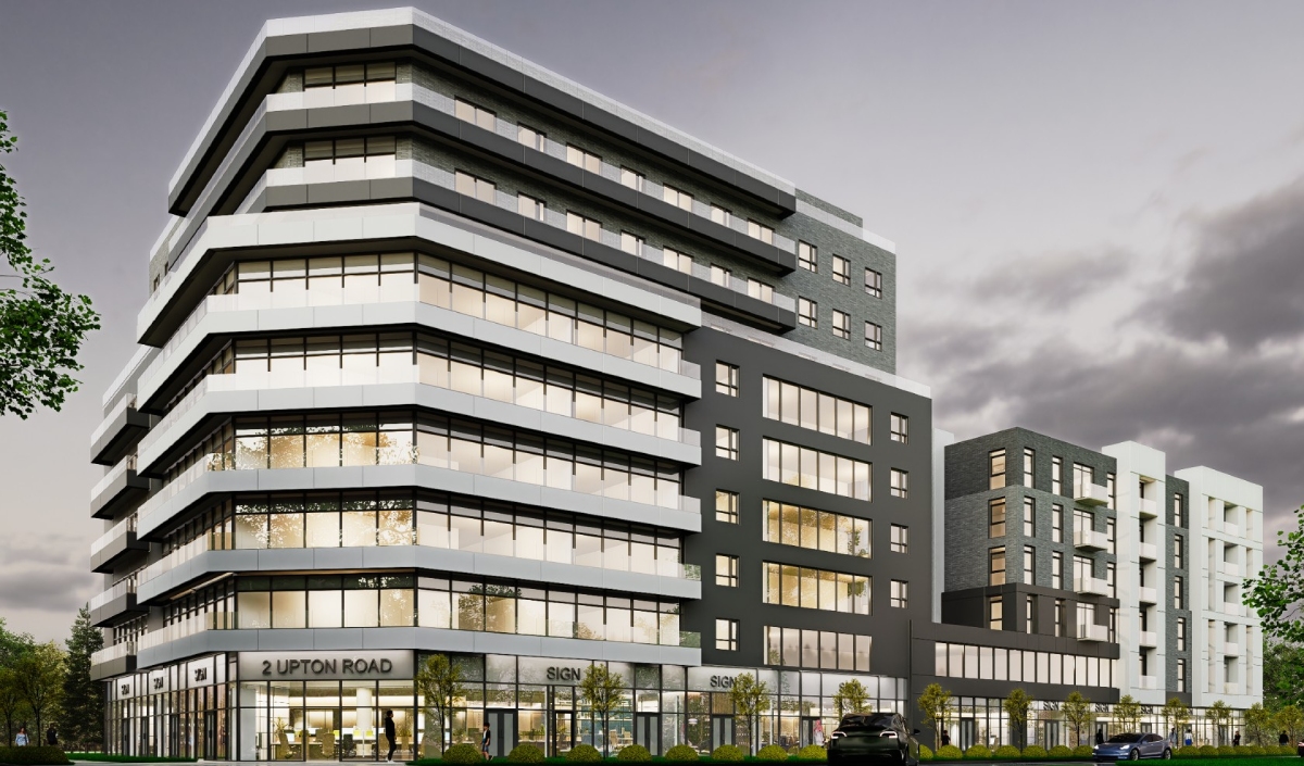Modern multi-story office and residential building with large windows and geometric design, photographed at dusk with trees and parked cars visible in the foreground.