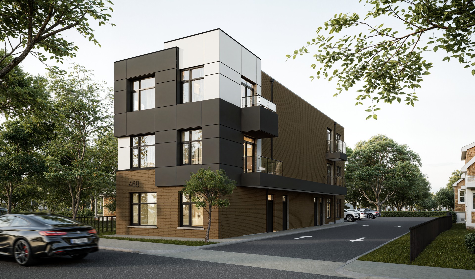 A modern three-story building with dark panels and large windows, located on a corner lot with trees and parked cars nearby.