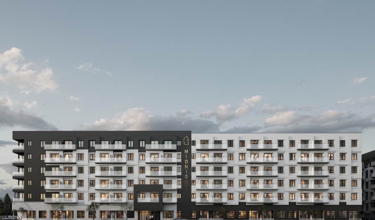 A modern mid-rise apartment building with black and white exterior, multiple balconies, and large windows under a cloudy sky.