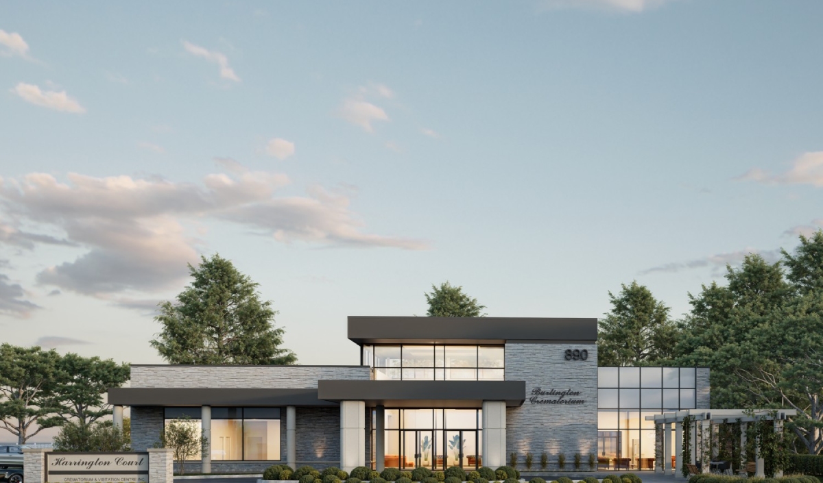 Modern two-story commercial building with large windows, surrounded by trees and landscaping, under a partly cloudy sky. A sign in front reads "Harrington Court.