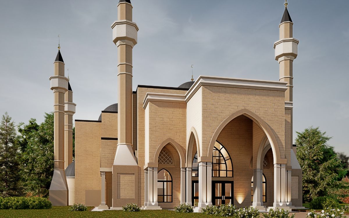 A modern mosque with four minarets, arched entrance, and beige stone exterior, surrounded by greenery under a partly cloudy sky.