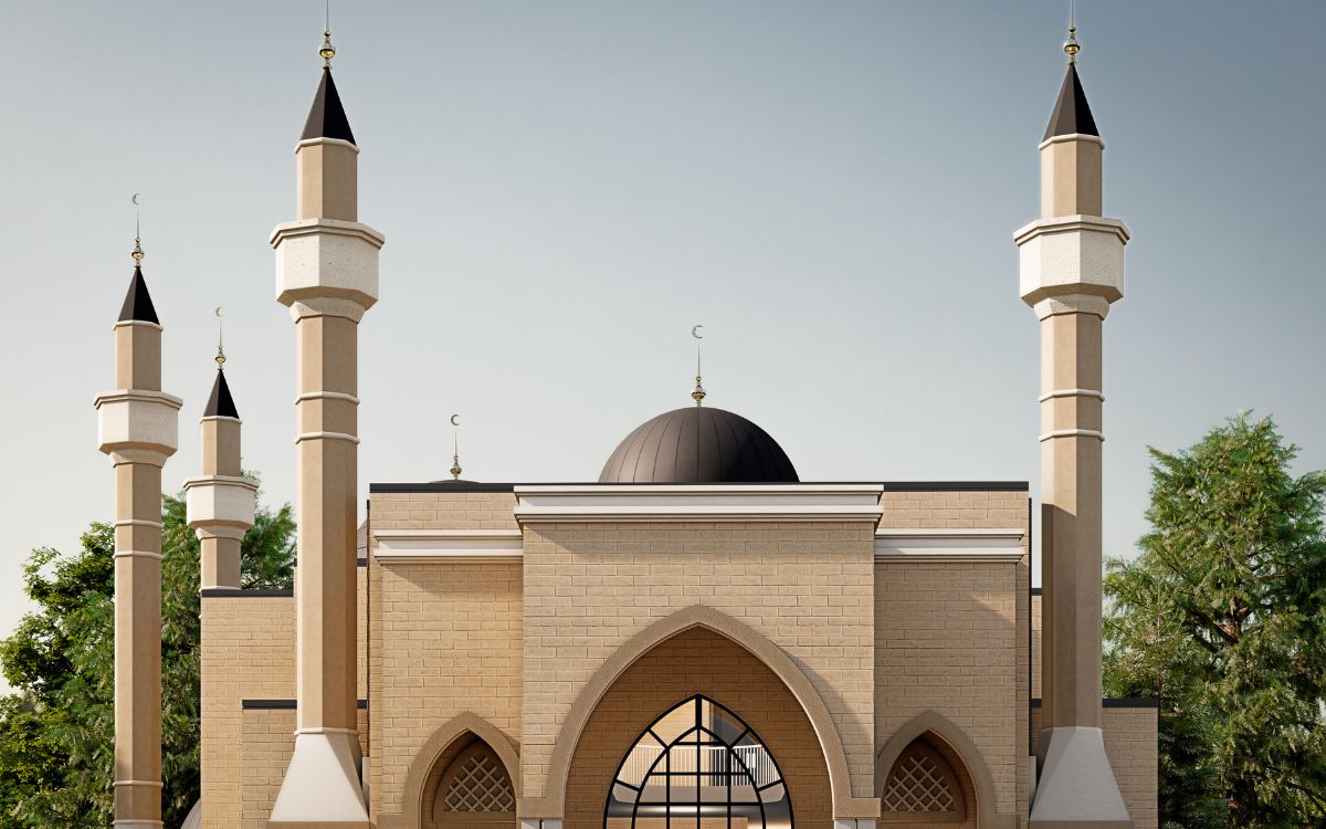 A beige mosque with four minarets, a central black dome, arched windows and doors, surrounded by trees under a clear sky.