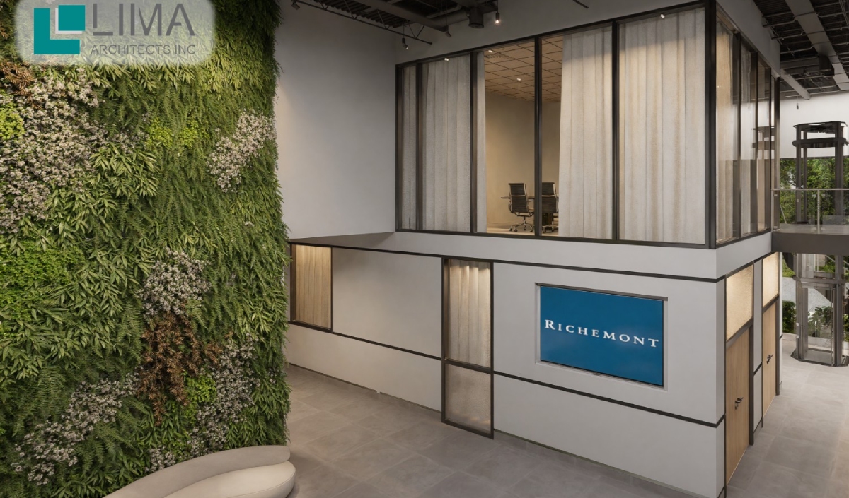 Modern office interior with a vertical green plant wall, glass-walled meeting room on the upper level, and a blue Richemont sign on the lower level.